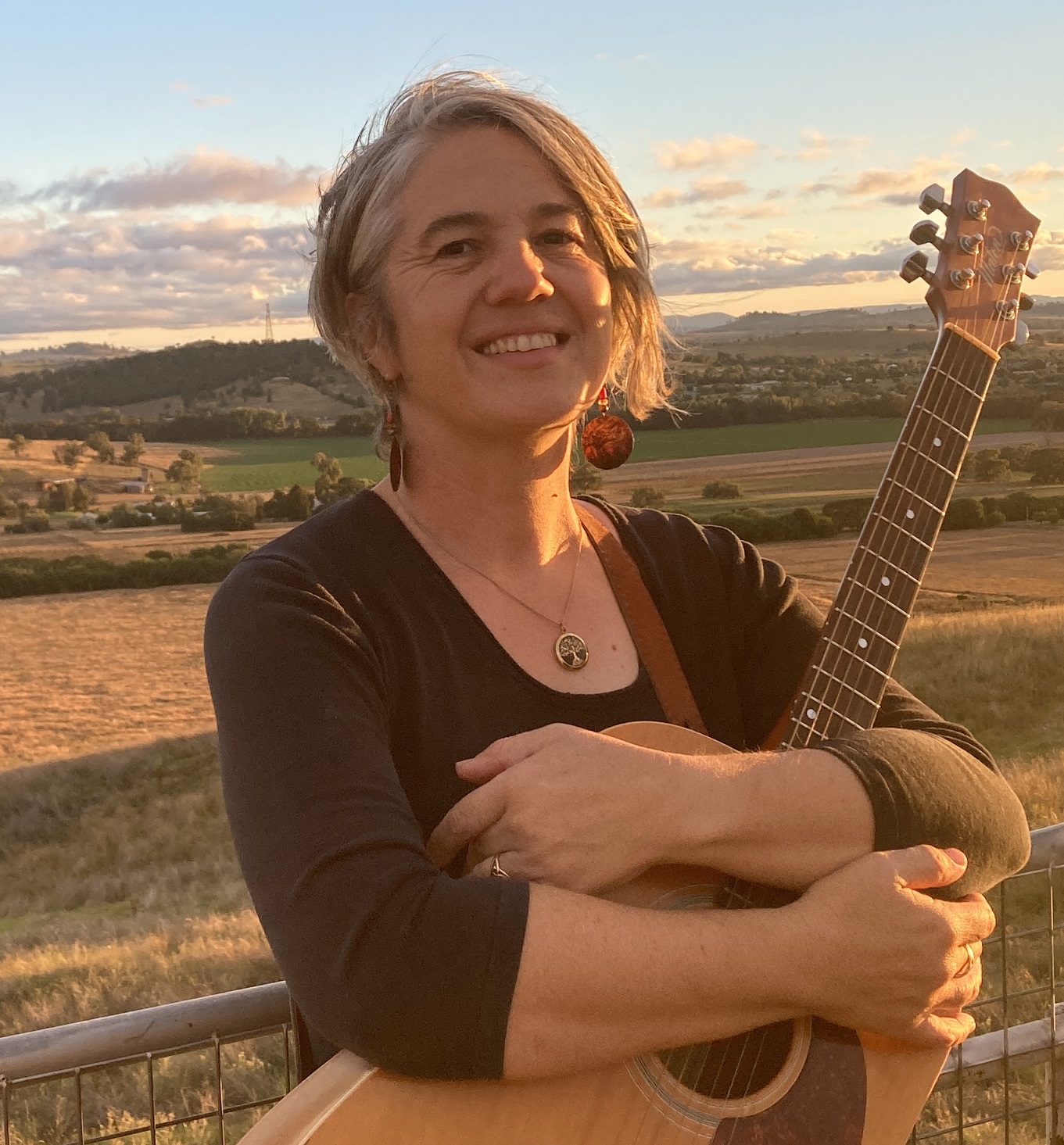 Nerida Cuddy standing in the landscape holding a guitar